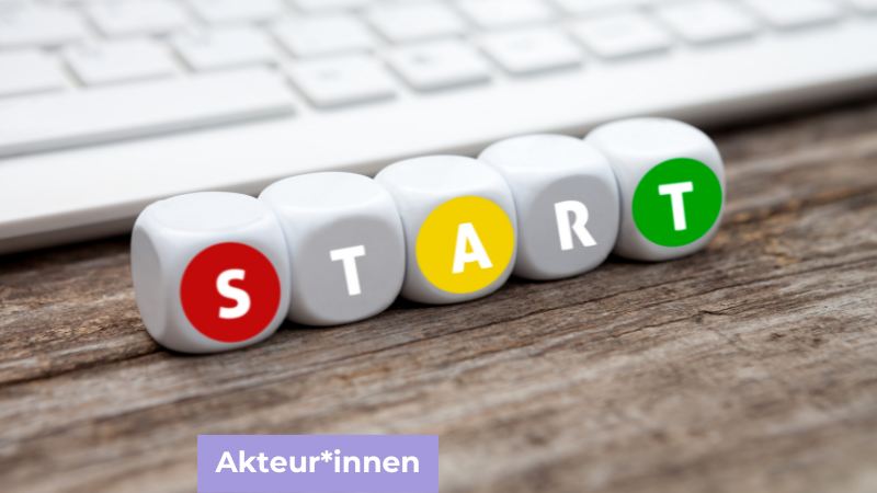 Fünf Würfel, die das Wort Start schreiben mit einer Tastatur im Hintergrund.